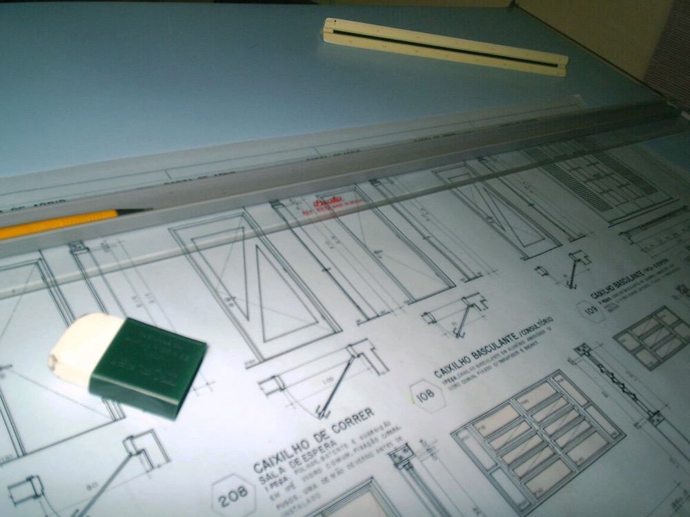 Tavolo da disegno con tavole tecniche di serramenti, matita e squadra